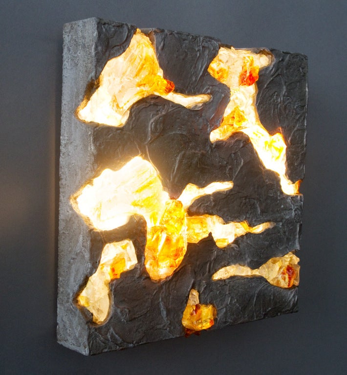 Este aplique está hecho de piezas de vidrio transparente y de color ámbar adheridas a la base de aluminio fundido. Hay dos bombillas internas de 25 vatios que iluminan los componentes de cristal por detrás. Se ha recableado el chapado eléctrico.