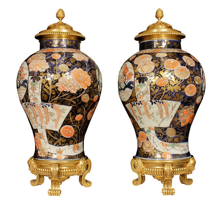 An exceptional and true pair of early 19th century Imari porcelain and ormolu lidded urns. Each spectacular and richly hued Imari porcelain urn is raised on an exquisite French ormolu Louis XIV st. base. Each reeded base has S scrolled foliate