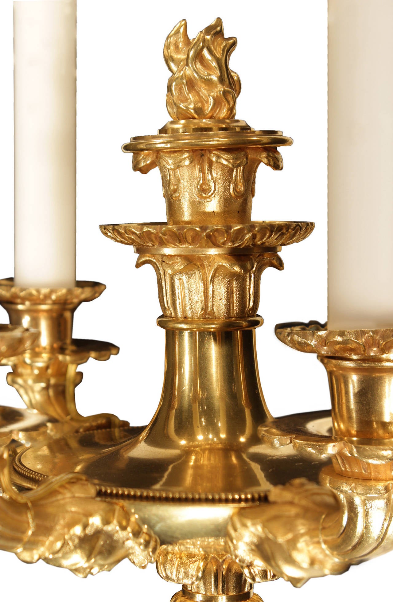 A stunning set of four French 19th century Charles X period ormolu sconces. Each sconce is centered by a richly chased bottom acorn finial. At the base of each of the five arms are wonderful and high detailed faces leading up the reeded supports to