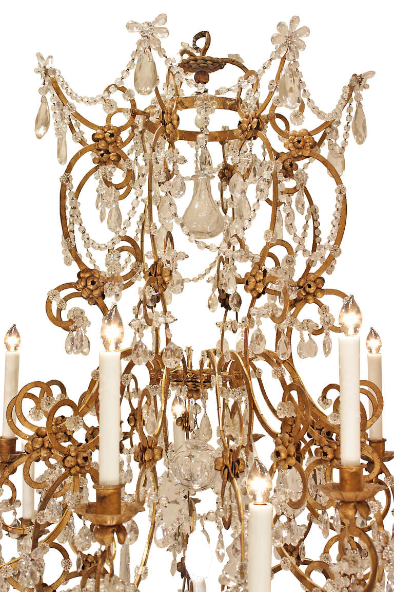 A spectacular large scale Italian mid 19th century Louis XV st. gilt metal and crystal seventeen light chandelier. At the bottom is a solid crystal ball below the giltwood acorn base supporting a central light. Each of the C scrolled and S scrolled