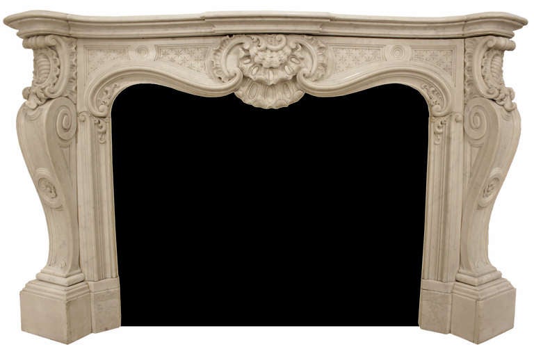 A very exuberant French 19th century, circa 1830, Louis XV st. intricately carved white Carrara marble mantel. This large scale mantel is raised on stunning volute jambs with a central rosette below a large cabochon scrolled capital amongst acanthus