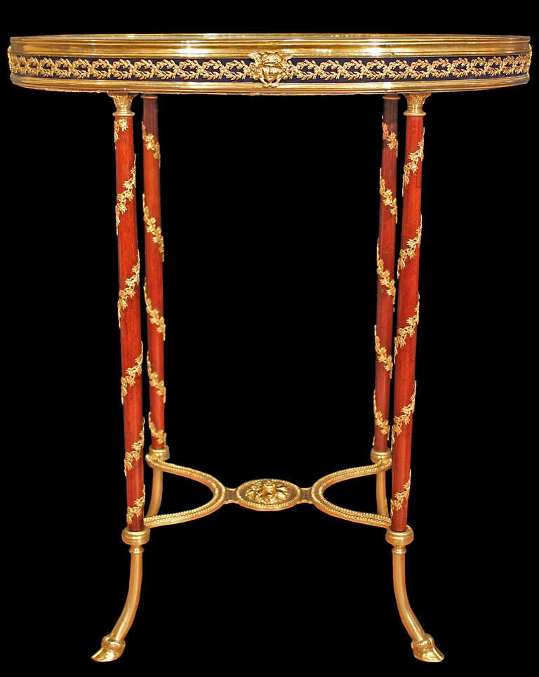 A spectacular French 19th century Louis XVI st. mahogany and ormolu side table. The table is raised by slender mahogany legs adorned with pressed gilt metal spiral foliate garlands and ormolu top capitols. The legs end in ormolu hoof shaped feet