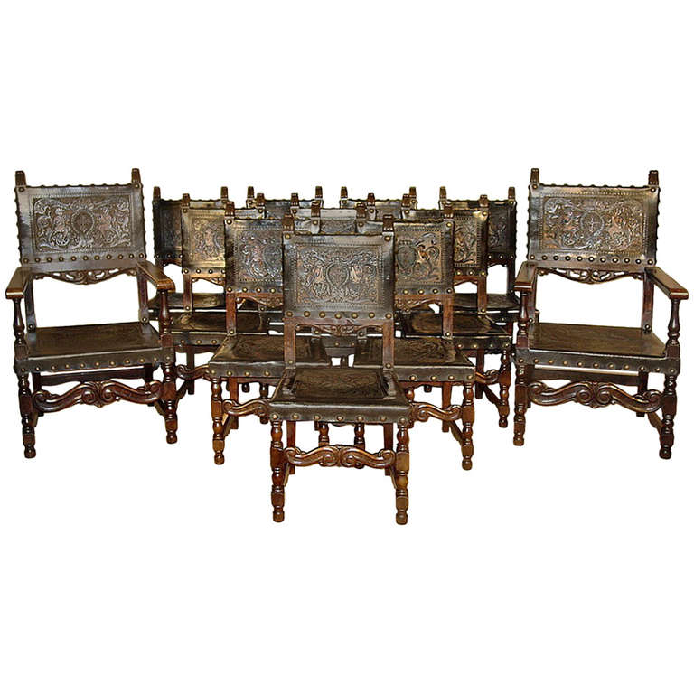 A stunning and complete set of mid 19th century, circa 1850, Spanish 
walnut dining chairs. The set with ten side chairs and two armchairs are upholstered with the original embossed and hand painted leather, finished with patinated brass nailheads,