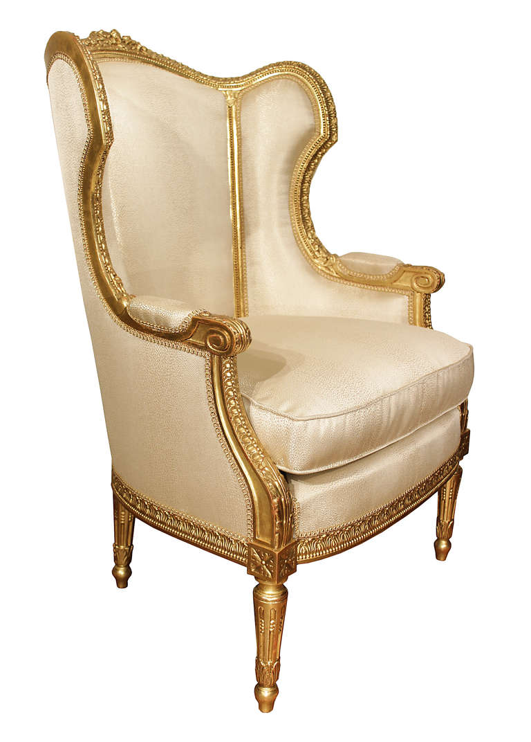 A very striking pair of French 19th century Louis XVI style giltwood Bergères à Oreilles. Each stunning wing chair is raised on tapered reeded supports with top rosette blocks and topie shaped feet. The impressive finely carved apron continues up