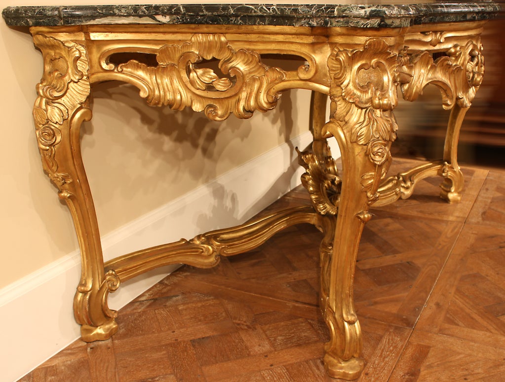 An important and exceptional pair of late 18th century Louis XV st. Roman freestanding giltwood consoles ‘Aux Cartouches’. Each large scale console is raised by ‘S’ scrolled cabriole legs and fancifully decorated by floral branches joined by a