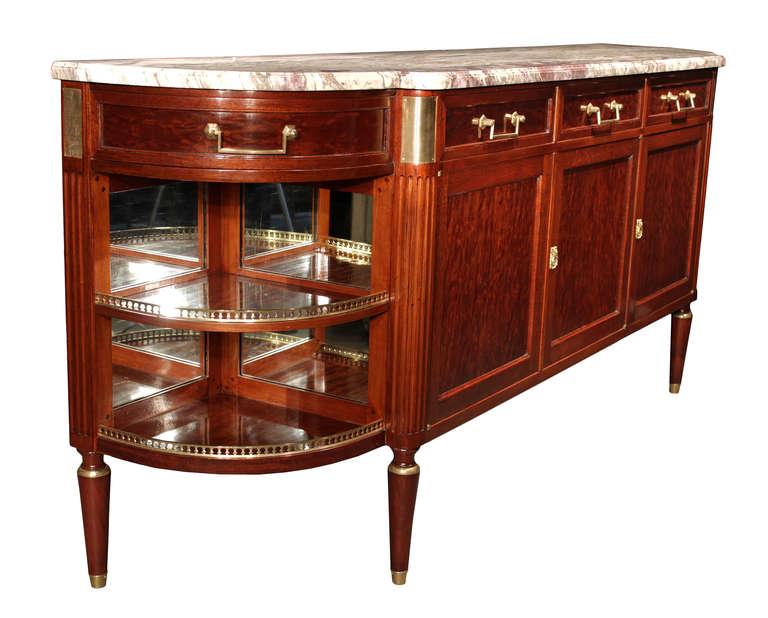 A very handsome French 19th century Louis XVI st. mahogany and ormolu buffet. The three door and five drawer buffet is raised on tapered legs with ormolu sabots. Above each leg is a fluted column topped with a reeded ormolu design element. The doors