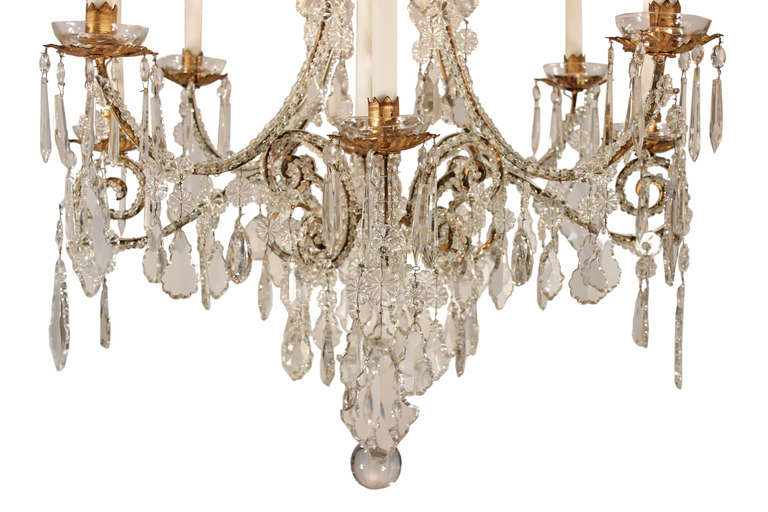 A stunning Italian 19th century crystal and gilt metal eight light chandelier. A crystal sphere hangs at the bottom below the scrolled beaded arms elaborately decorated with kite shaped crystals. Each arm ends with a gilt metal bobeches with crystal