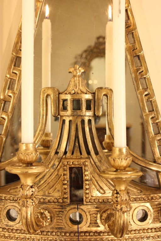 A very attractive and elegant pair of monumental mid 19th century Italian giltwood Mongolfière shaped sconces. Each sconce with a carved bottom scrolled foliate finials has a pierced fluted design with mirror plate back below carved rosettes and the