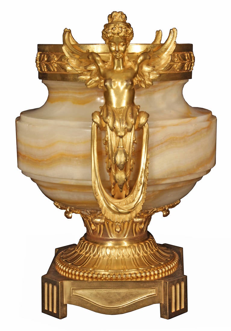 A stunning French 19th century neoclassical St. Onyx and ormolu urn. The urn is raised on a square ormolu base with reeded supports. At the base of the urn is a finely chased socle supporting the beautiful onyx urn. At each side are finely chased