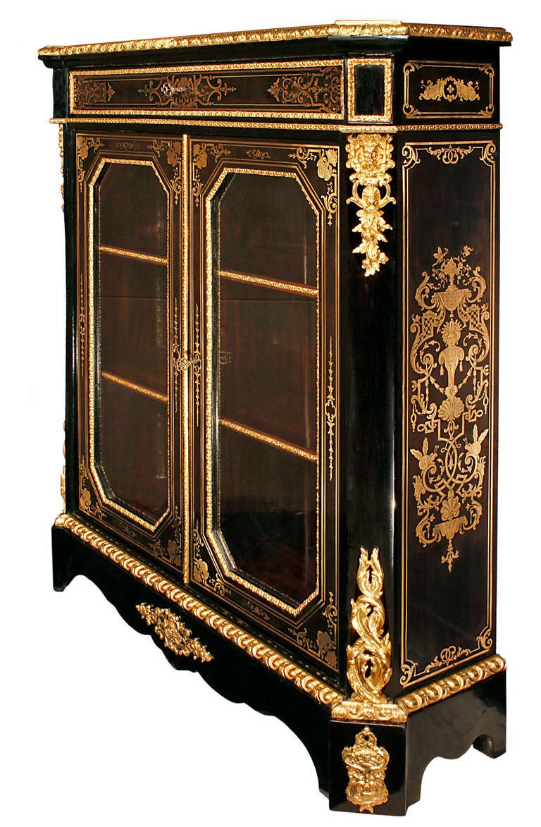 A very high quality pair of French mid 19th century Napoleon III period Boulle vitrines. Each cabinet in ebony with brass inlay and ormolu mounted is raised by obtruded square blocks with ormolu masculine masks. The scalloped shaped frieze has a