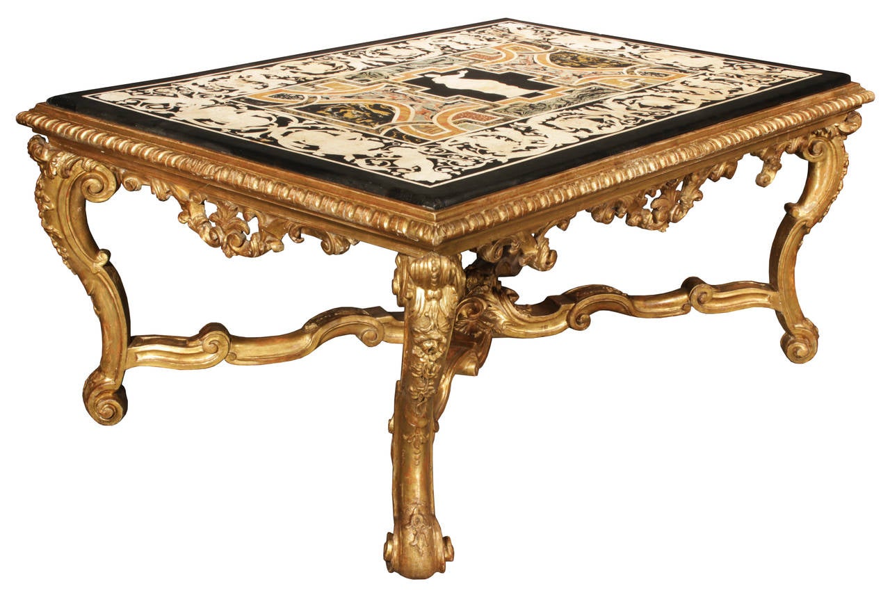 A magnificent Italian 18th century Scagliola top fitted into a 19th century Louis XV style carved giltwood coffee table. The table is raised on elaborately scrolled legs with acanthus leaves joined by a scrolled X stretcher with foliate central