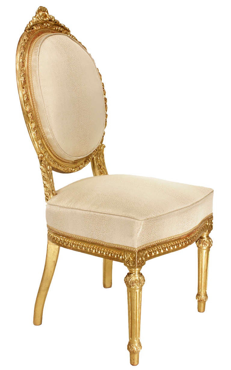 A magnificent set of eight Italian mid 19th century Louis XVI st. giltwood dining chairs. Each of the six side chairs and two armchairs is raised by circular reeded front legs with straight tapered back legs. The curved frieze is decorated by a