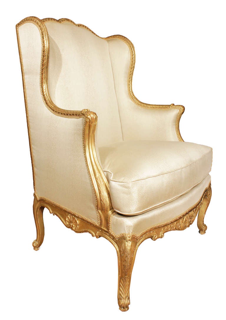 A high quality large scaled pair of mid 19th century French Louis XV giltwood Bergères a Oreilles. Each wing chair is raised by cabriole legs with carvings of shells and acanthus leaves. The scalloped shaped frieze is likewise decorated with a