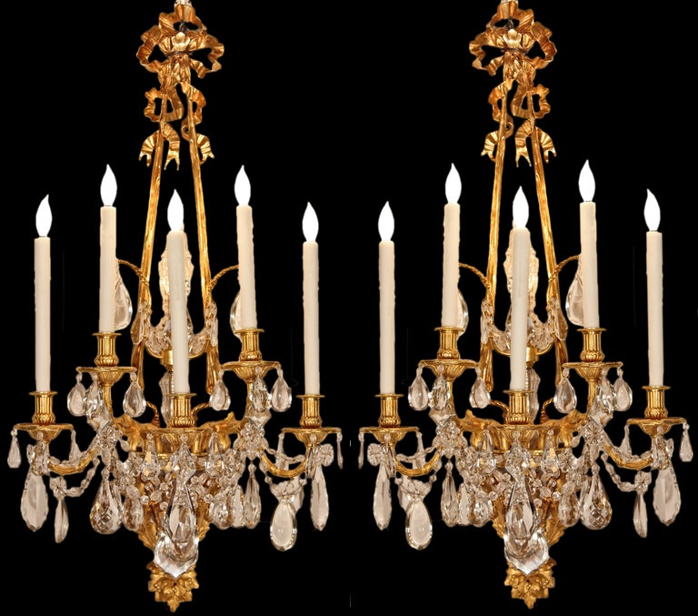 A sensational quality and large scale pair of French 19th century  Louis XVI st. five arm ormolu and Baccarat crystal sconces, signed Henry Vian. Each sconce has a pierced and richly chased backplate with foliage and acanthus leaves. Centered below
