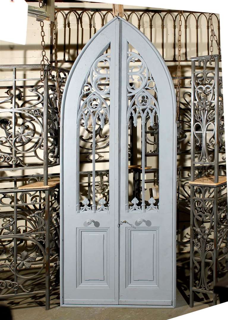 Pair of 19th century French iron conservatory doors with Norman arch and gothic motifs restored in a frame, circa 1870.  Each door has a dummy mounted center knob.  This entryway has been bead blasted, primed and is now ready for paint.  The