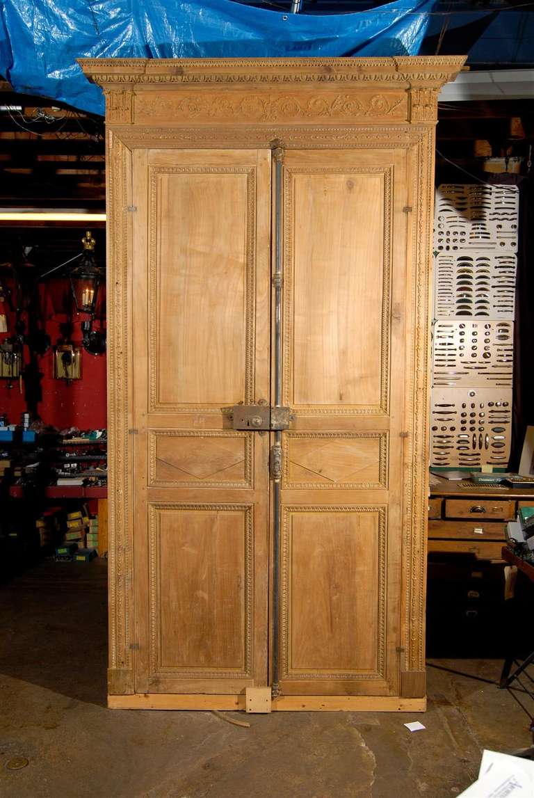 19th century French entryway with carved doors, facing, and overdoor, circa 1870.  Each door has 3 panels.  Some hardware is included with the entryway, such as hinges, a cremone bolt, and rim lock.

Two entryways available - however sold