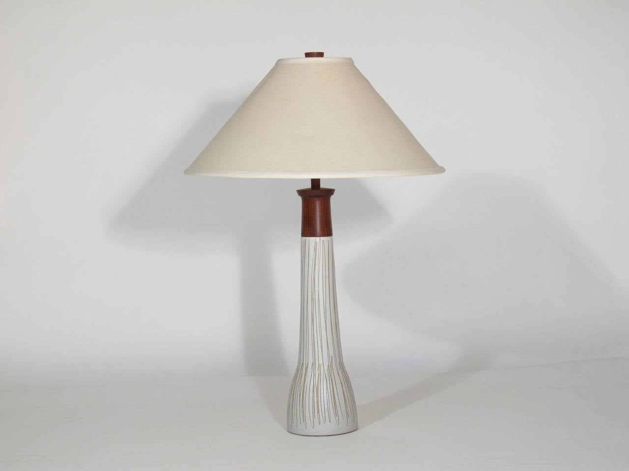 White glazed ceramic lamp with walnut neck and finial designed by Gordon Martz for Marshall Studios. Shown with original shade.