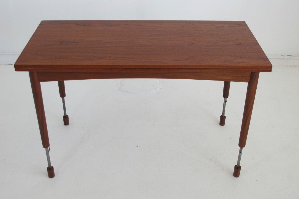 Mid-century Hans Olsen designed table extends from coffee table to full height dining table. Feet extend from legs to increase height; exposing inner steel supports and locking mechanism. Top twist and flips open to double surface size. Exposed