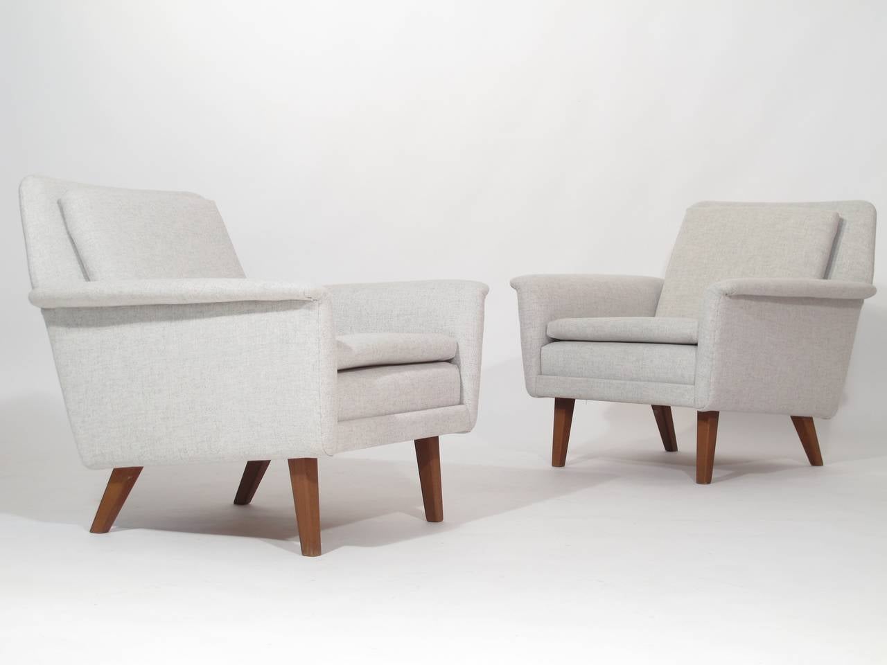 Pair of mid century Scandinavian upholstered lounge chairs designed by Hans Olsen and distributed by Illum Boligus, Denmark. Solid wood frame with loose seat and back cushions, newly upholstered in off-white Danish wool textile. Raised on tapered