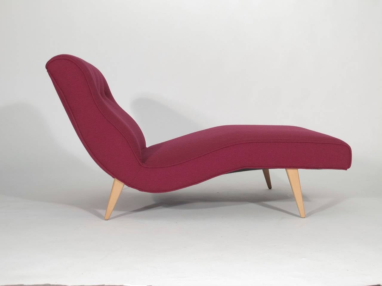 Chaise lounge crafted of solid wood frame and raised on tapered maple legs, newly upholstered in magenta/burgundy wool textile with button tufted back.