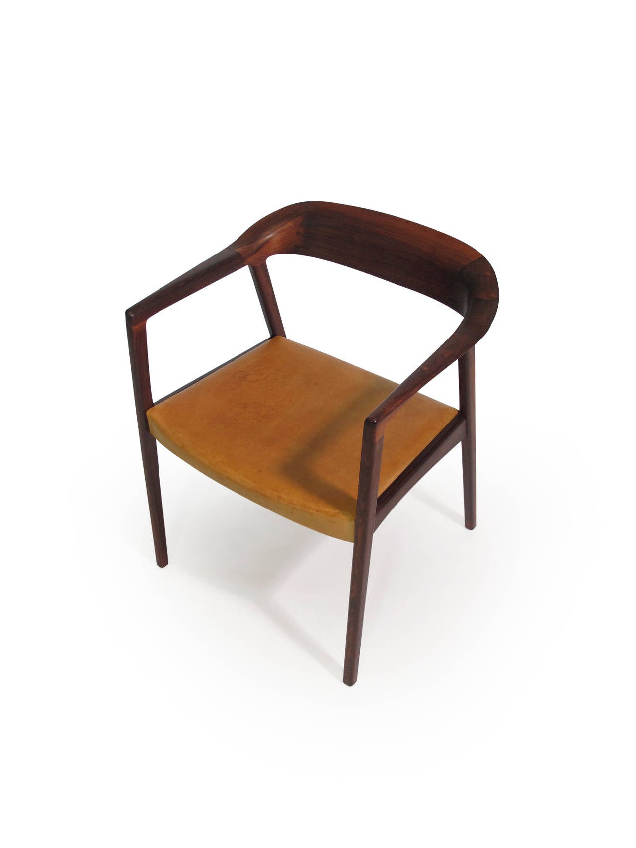 Elegant mid-century arm chair handcrafted of solid Brazilian rosewood with exposed joinery in the back with original distressed leather seat.