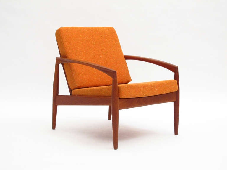 Danish teak lounge chair designed by Kai Kristiansen for Magnus Olesen. Solid teak frame with slat back, newly upholstered cushions in an orange wool.