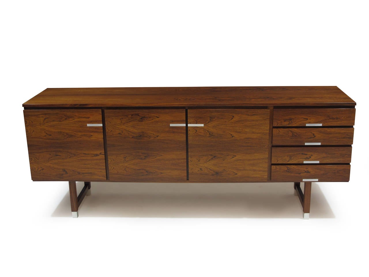 Rosewood credenza designed by Kai Kristiansen. Features a horizontal book match grain on doors with contrasting aluminum inlay; white oak interior with adjustable shelves. Raised on square legs with capped feet of aluminum.