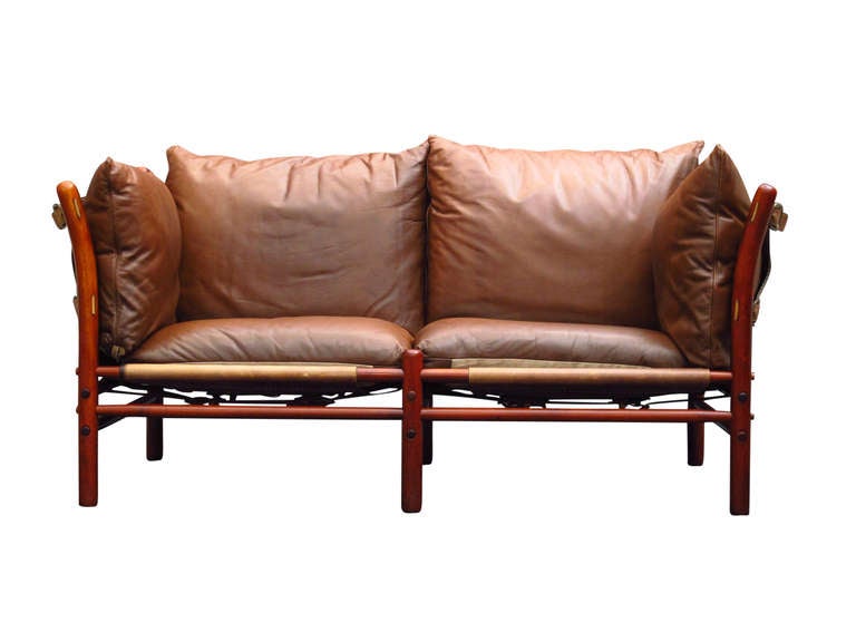 Leather Safari two-seat sofa designed by Arne Norell, Sweden. The stained beech wood frame is held together by series of leather straps and wood dowels. Original leather cushions.