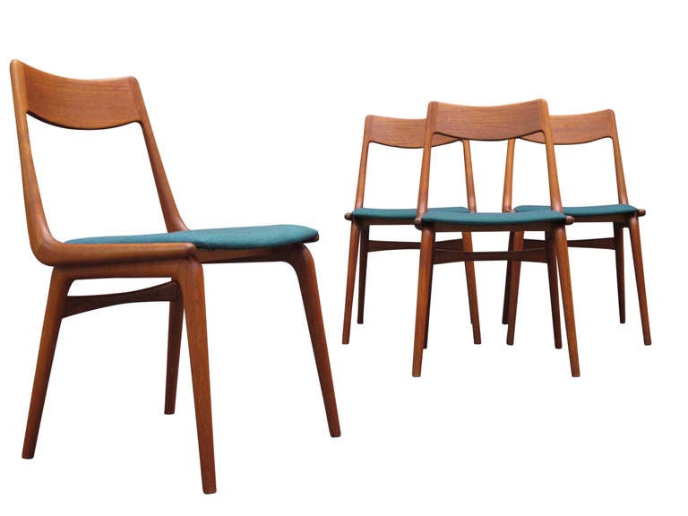 Four teak boomerang dining chairs designed Erik Christiansen for Slagelse. Solid teak frames with newly upholstered seats in a teal scandinavian wool textile.