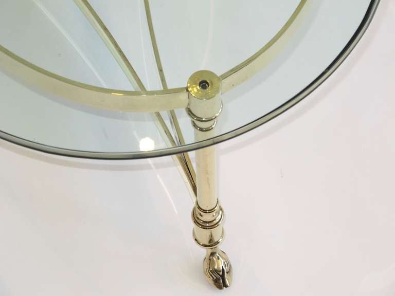 Elegant LaBarge polished brass coffee table with curved stretchers and four legs raised by hoofed feet. Oval green tinted glass with ogee edge.