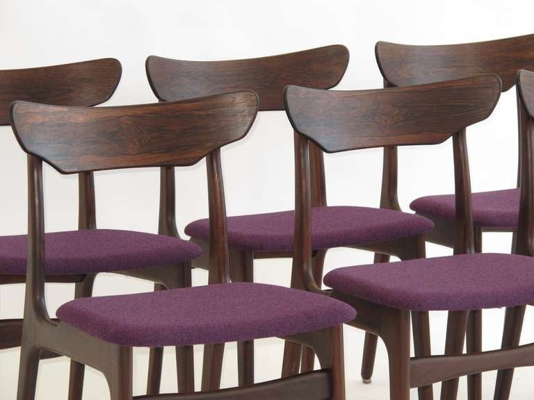 Six Mid-century Danish Brazilian Rosewood dining chairs. The rosewood features rich dark color and stunning grain patterns across each of the curved backs. The chairs have been newly upholstered in aubergine/black wool fabric. Upholstery options