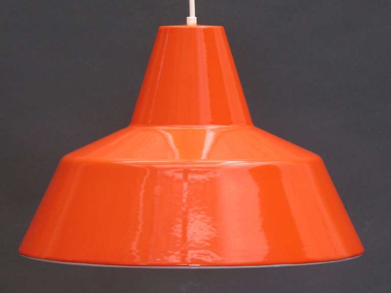 Enameled steel pendant lights with orange exterior and white interior. Designed by Arne Jacobsen for Louis Poulsen. Seven available.