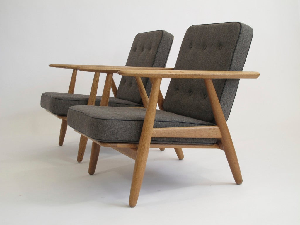 Pair of lounge chairs deigned by Hans Wegner for Getama. Solid oak frame with period finish; removable inner spring cushions with original wool fabric. Custom upholstery available.