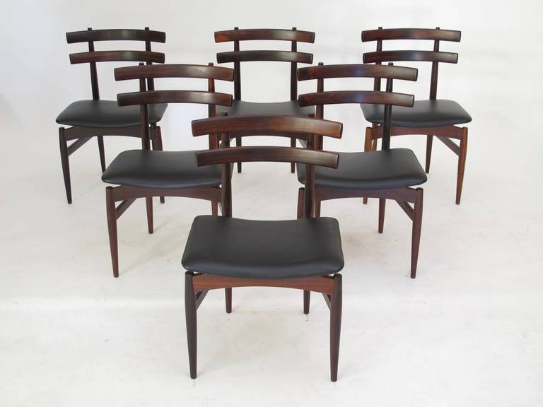 Finely crafted solid Brazilian Rosewood dining chairs designed by Poul Hundevad, Denmark. Features solid Rosewood with sculpted curved backs and book-matched grain in center. Floating seats raised on elegant tapered legs. Exquisitely crafted.