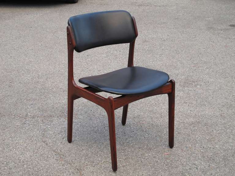 Set of 12 dining chairs design by Erik Buck for Poul Dinesen. Model #49.  Rosewood frames with floating seats  and curved backs upholstered in original black vinyl. Custom upholstery options available upon request. 

18 Chairs are available.