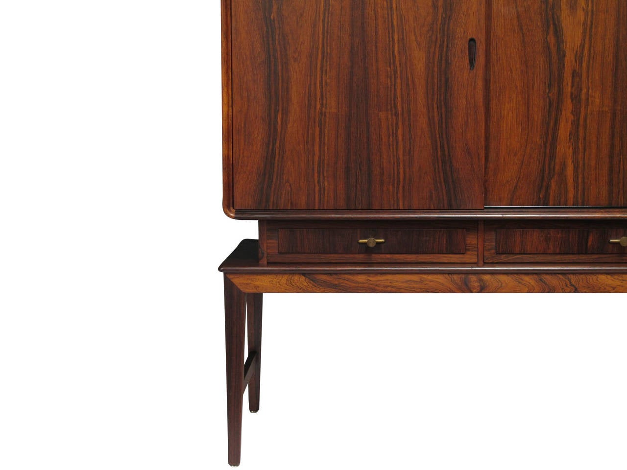 Early 1950s Rosewood sideboard with stunning book-matched grain and four sliding doors with adjustable shelves; above series of four drawers with brass pulls. Raised on stilted rosewood legs. Fine Scandinavian craftsmanship and joinery.