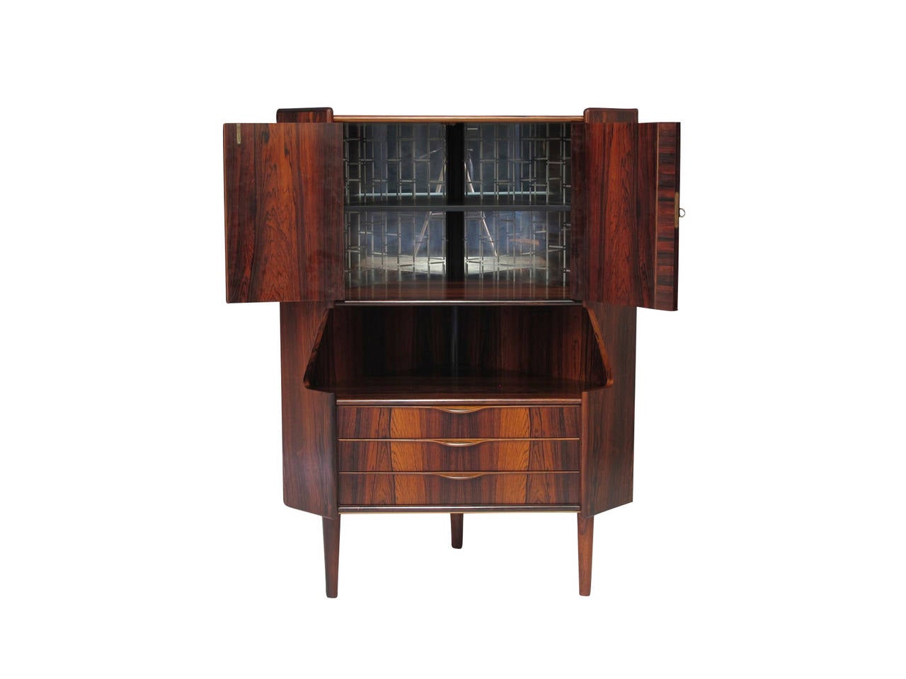 Mid-century Brazilian rosewood corner cabinet with with rich book-matched grain patterns. Locking doors reveal an interior bar with mirrored back; open space and three drawers below. Raised on round tapered legs. Requires 24.75