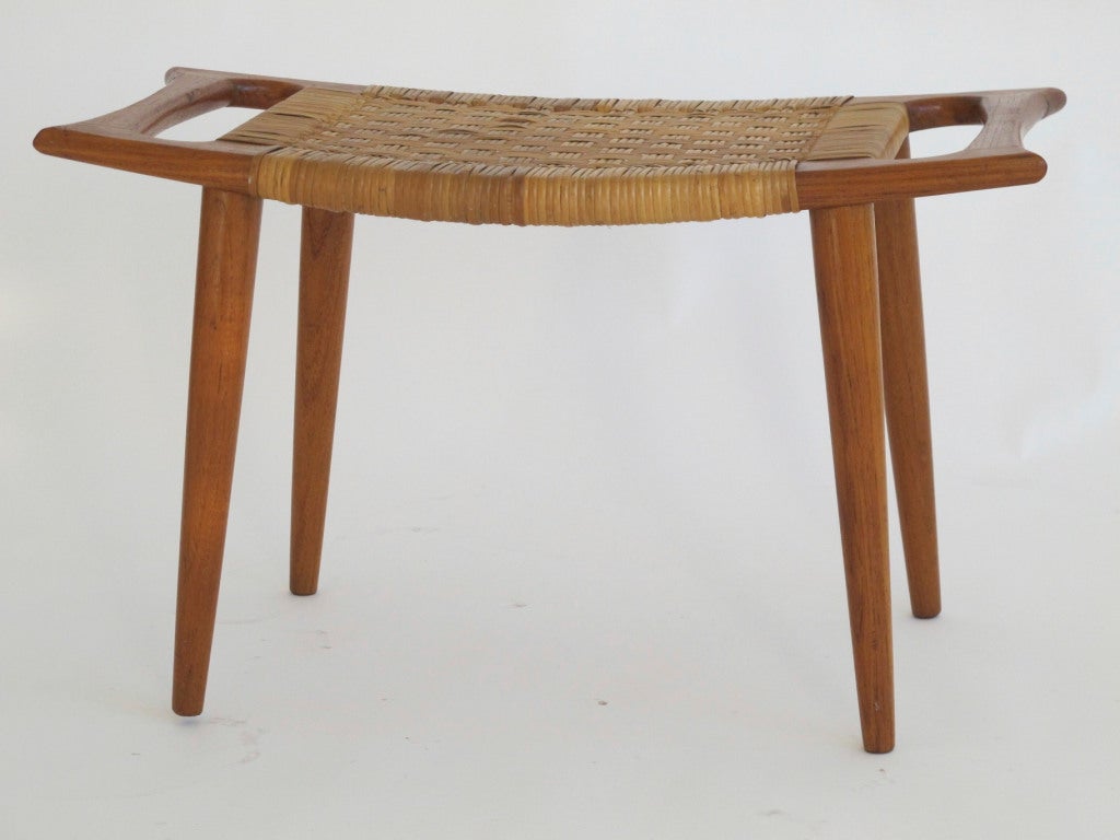 Danish ottoman with teak legs and woven cane seat.