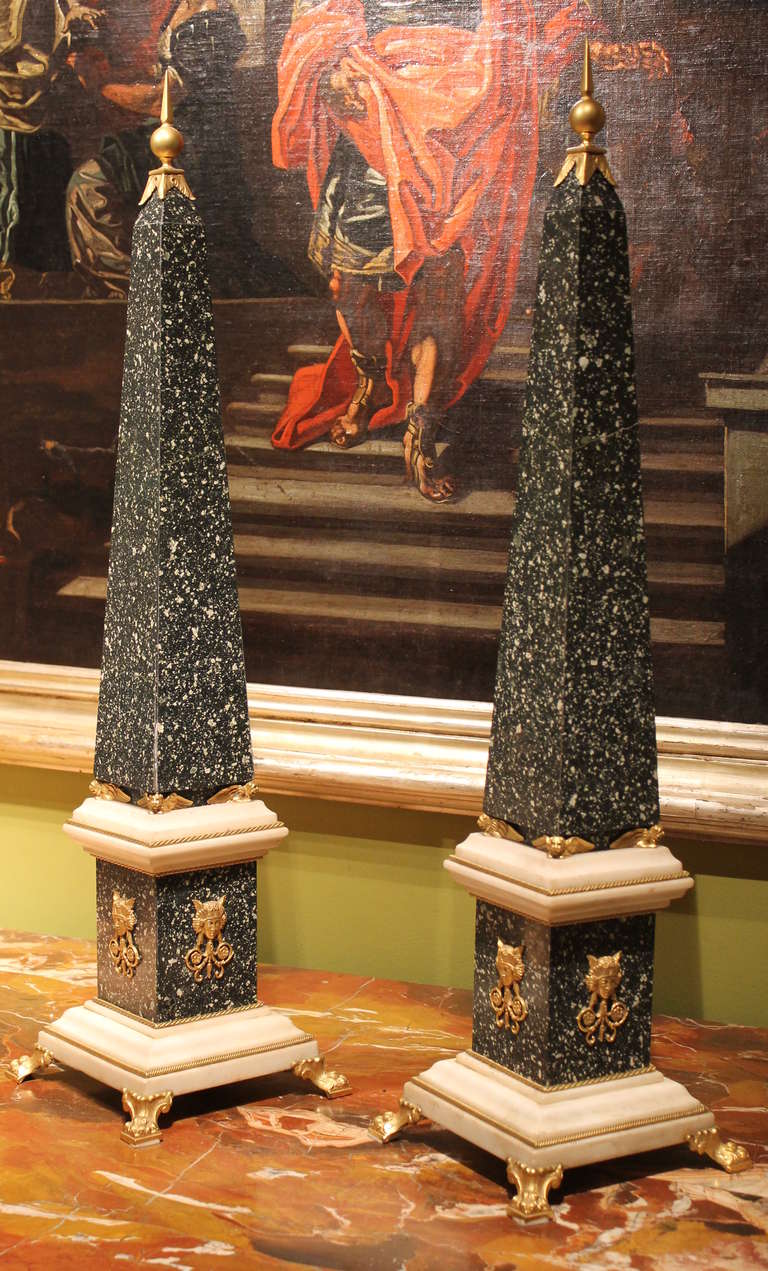 Antique high end pair of Italian (Rome) Empire period obelisks made of precious green porphyry slabs and solid white Carrara marble enriched by finely hand chiseled ormolu mounts throughout. 
Green and white marble alternate harmoniously, while each