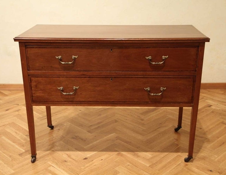 This lovely 19th Century walnut wood chest of drawers with crossbanded mahogany top and drawers has two drawers with its original bronze handles. The commode raises on brass caster feet.
Thanks to its simply lines and its narrow proportion this
