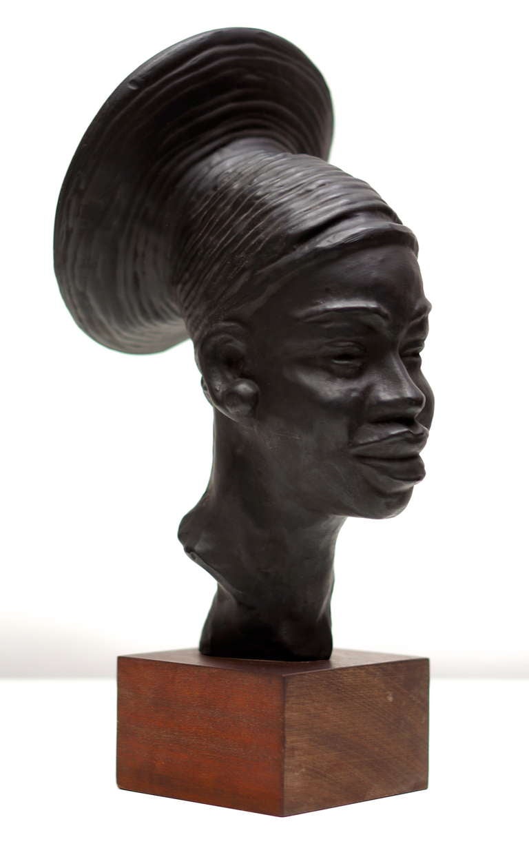 A magnificent work of art by Belgian artist Paul Serste (° 1910, + 2000) from the 1930s. Terra cotta head of a African woman (Manguebetu tribe) with brown patina, signed by the artist. This beautiful piece stands on its original wooden plinth. A