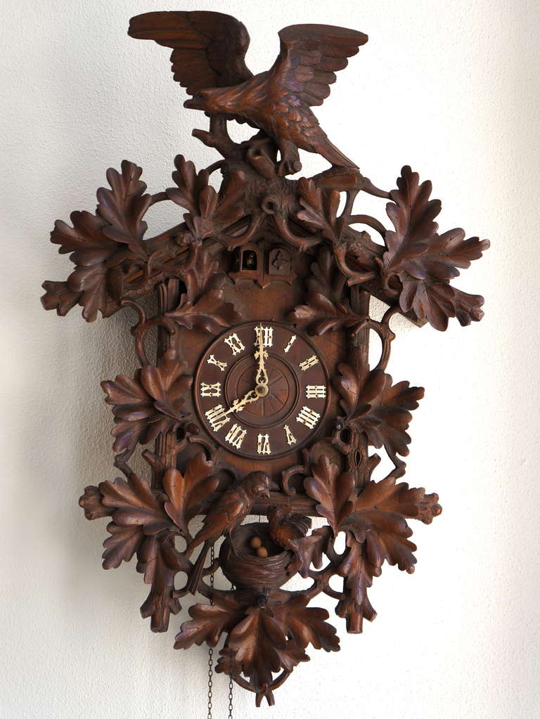 Carved extensively with oak leaves, an eagle with stretched wings on top, a cuckoo sitting on its adoptive parents nest in the bottom, with two cuckoos appearing alternatingly from a double door.