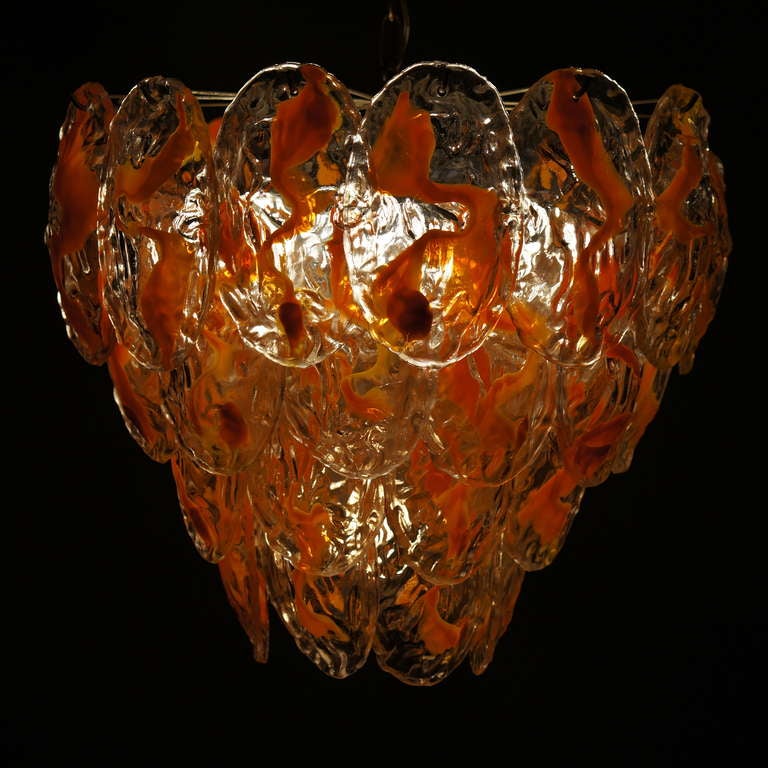 Grand lustre en verre de Murano avec quatre rangées de feuilles en verre transparent et orange. Le corps est composé de 40 verres en forme de feuilles suspendus à un cadre chromé.