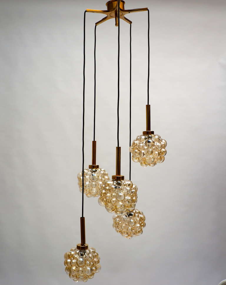 Impressive brass and amber toned glass bubble globe, five pendants, chandelier, with thick amber colored bubbled glass globes, handblown and finished by hand, designed by Helena Tynell, by Limburg, Germany, circa 1960s.