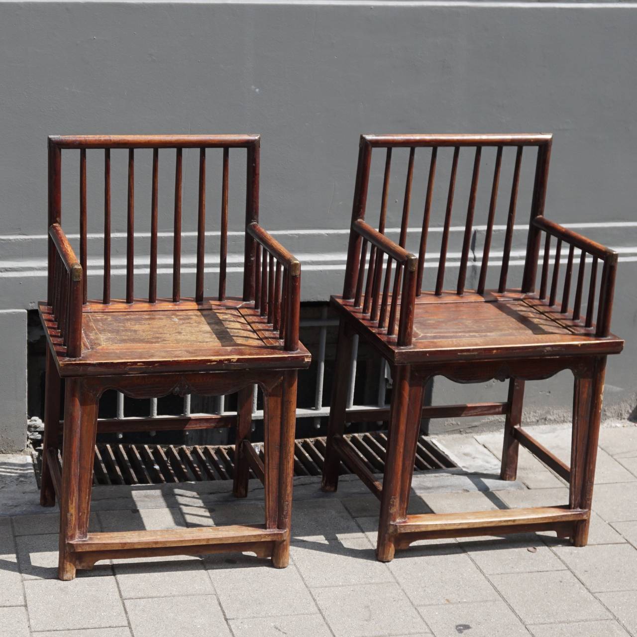 The chairs are constructed with a back top rail, which is supported by round posts that continue into the back legs. It houses seven curved round section spindles. Each stepped armrest houses five spindles and is supported by round posts that