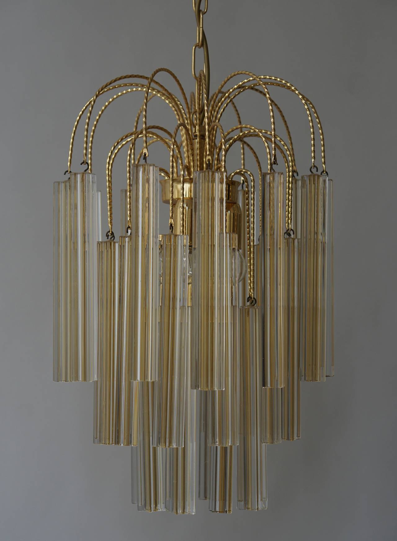 This exceptional Mid-Century pair of Modernist Camer chandeliers by Venini features 32 individually handmade Murano glass triedre prisms. 
The high quality crystal reflects the light beautifully with its elegant shape. This chandeliers has four