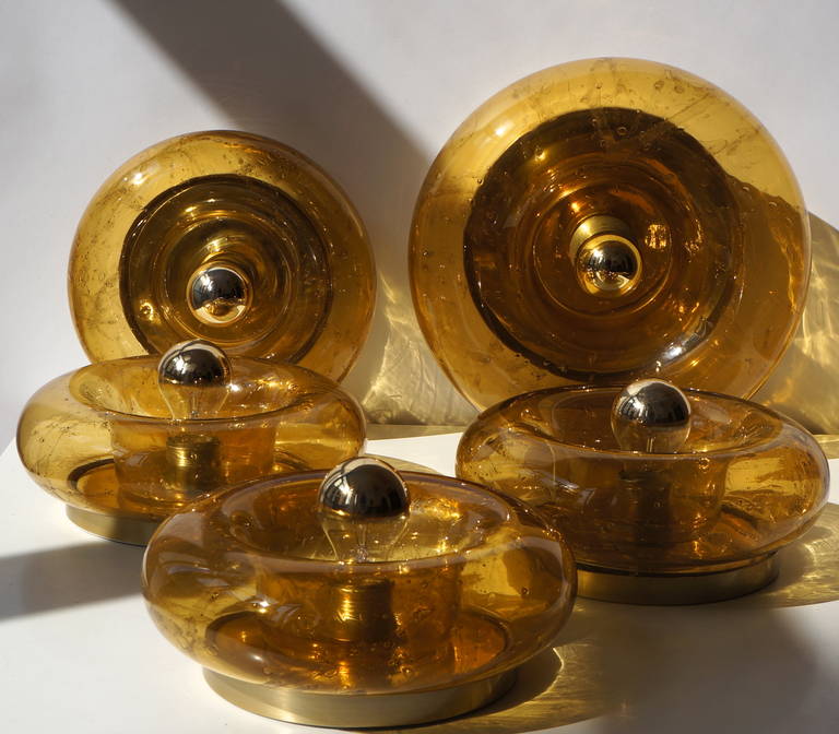 Nine glass flush mount lamps by Doria featuring a donut shaped glass ring, the glass rings have embedded swirls and bubbles.

There are a total of six large ones available, three of which have the dark amber color and three have the lighter amber