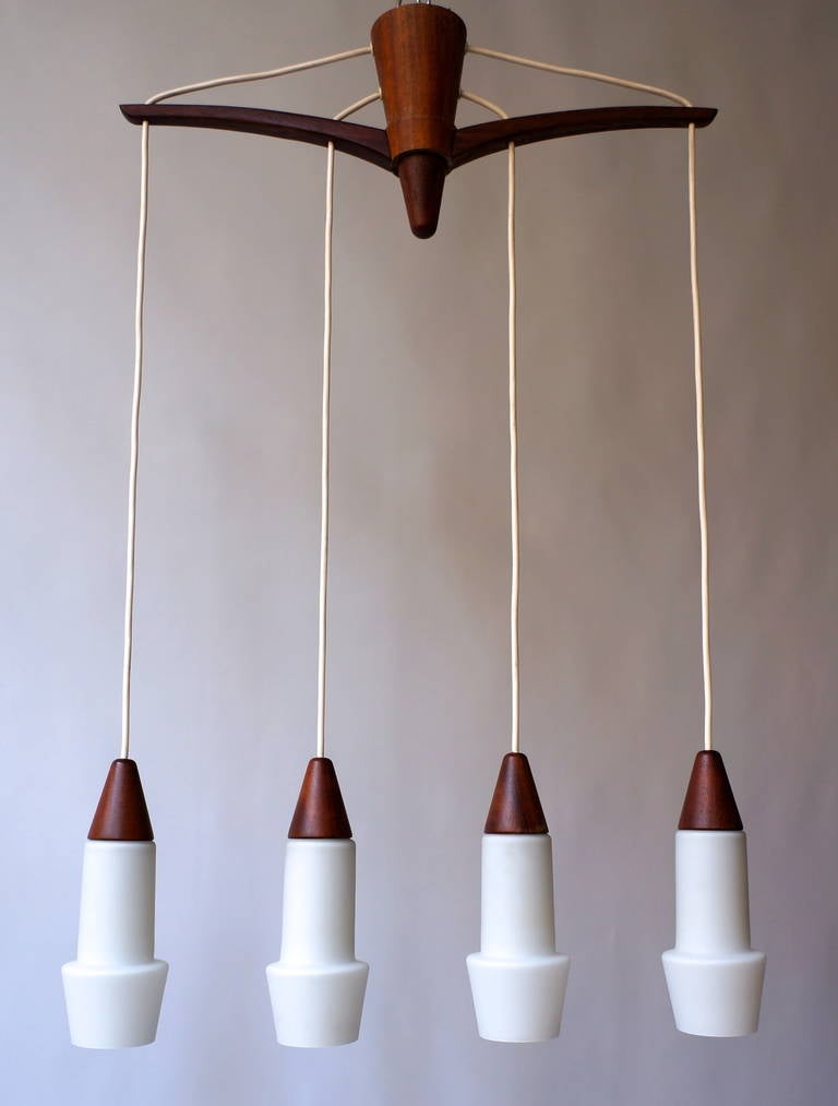Uno & Osten Kristiansson (Suède, 1925-2009), rare plafonnier suspendu en bois et verre opalin à quatre lumières Luxus. 

 Les frères designers Uno & Östen Kristiansson sont connus pour leurs luminaires et miroirs et ont été particulièrement actifs