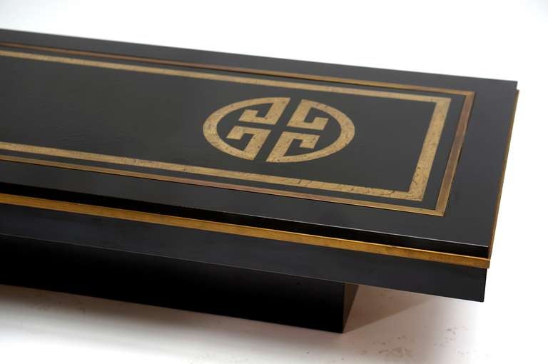 Mesa de centro italiana de los años 70, de De Nisco, de madera recubierta de melamina negra; la superficie superior es una placa de metal esmaltado con inserción de elementos metálicos y está unida por una tira de metal dorado. Algo de oxidación en