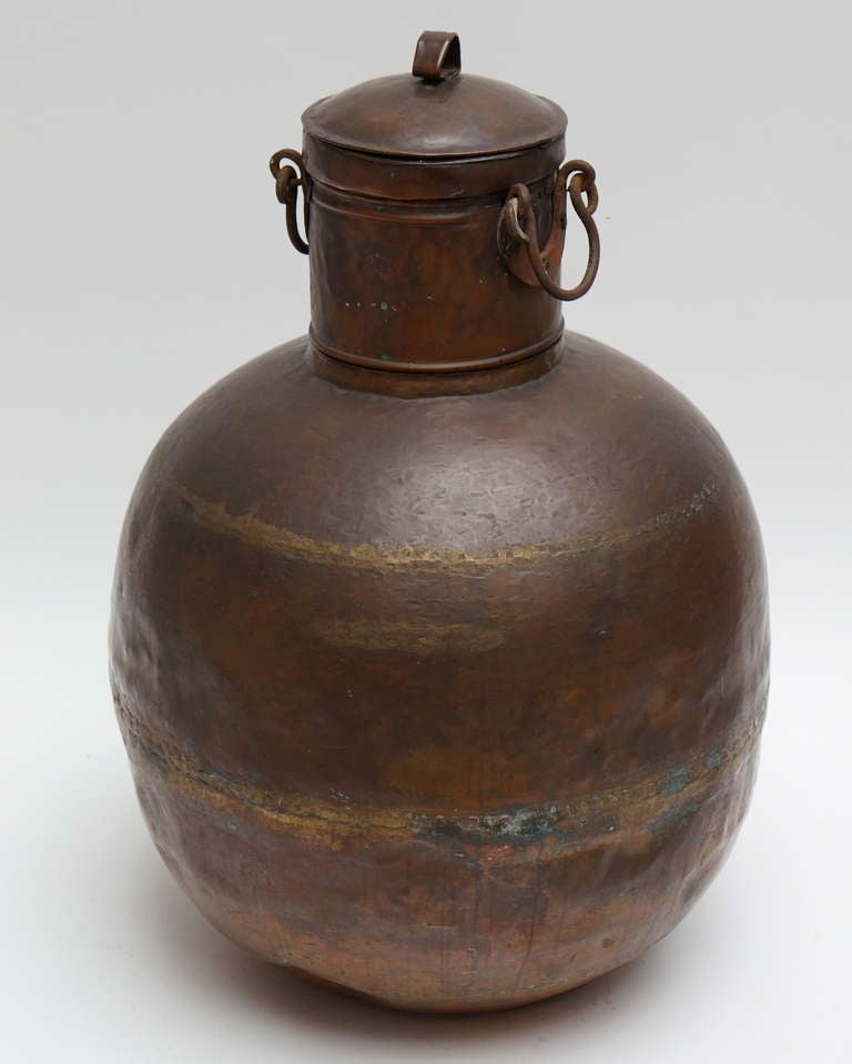 A tall copper covered container with two hinges at the neck.
Lovely patina. Probably of Indian origin.